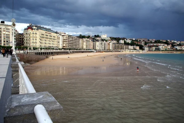 Şehrin kıyı şeridi, La Concha Körfezi 'nin kumlu plajı, arka planda fırtınalı bulutlar, Donostia-San Sebastian, Bask Ülkesi, İspanya - 12 Mayıs 2017
