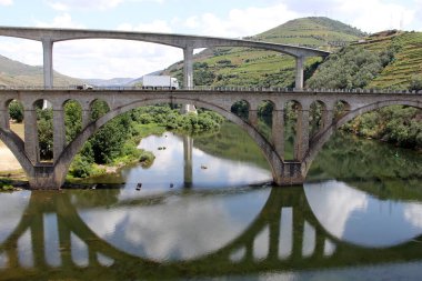 Portekiz şarap bölgesinde Porto Nehri 'nin doğusundaki Douro Nehri üzerinde köprüler, arka planda yamaçlarda teraslı üzüm bağları, Peso da Regua, Portekiz - 24 Mayıs 2023