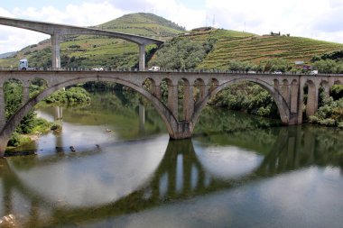 Portekiz şarap bölgesinde Porto Nehri 'nin doğusundaki Douro Nehri üzerinde köprüler, arka planda yamaçlarda teraslı üzüm bağları, Peso da Regua, Portekiz - 24 Mayıs 2023