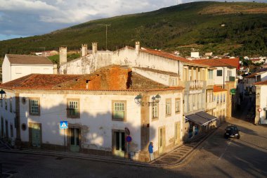 Dilapidated townhouses at the cobblestone street corner in sunset light, hilly countryside in the background, Torre de Moncorvo, Portugal - May 23, 2023 clipart