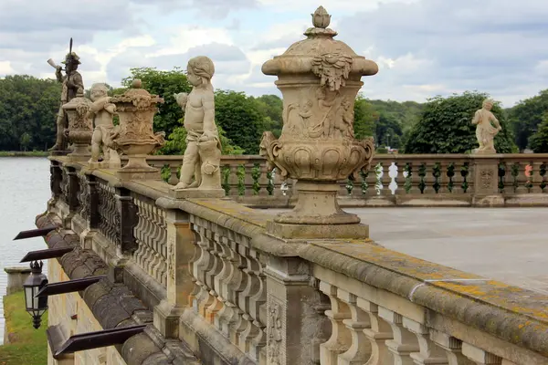 Taş heykeller ve vazolar, Moritzburg Kalesi 'nin teras balyasının süslemesi, 18. yüzyıl Barok mimari anıtı, arka planda kale parkı manzarası, Moritzburg, Dresden yakınlarında, Saksonya, Almanya - 4 Temmuz 2024