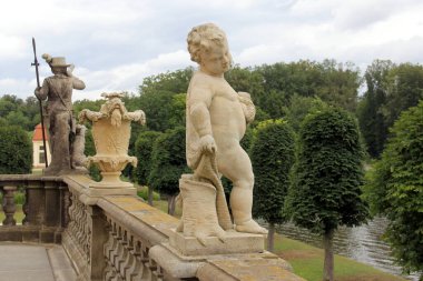 Taş heykeller ve vazolar, Moritzburg Kalesi 'nin teras balyasının süslemesi, 18. yüzyıl Barok mimari anıtı, arka planda kale parkı manzarası, Moritzburg, Dresden yakınlarında, Saksonya, Almanya - 4 Temmuz 2024