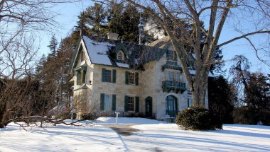 Linwood House, 19th-century cottage on the Norman Rockwell Museum grounds, winter view with a snow-covered lawn in the foreground, Stockbridge, MA, USA - February 14, 2016 clipart