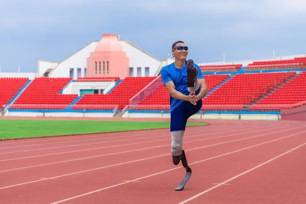 An Asian speed runner, equipped with two prosthetic blades, commences his warm-up with high knee jumps at the sports stadium