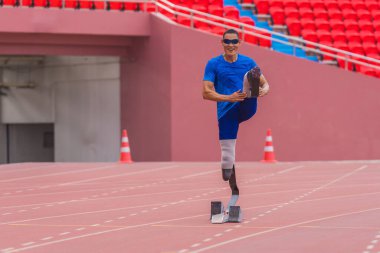 Stadyumda erkek hız koşucusu, yarıştan önce yüksek diz atlamasıyla ısınıyor.