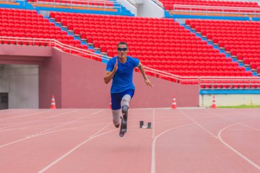 Protez kullanan inatçı Asyalı sporcu, stadyum pistindeki rekorunu kırmak için hızla havalanıyor. Hareket bulanıklığı, hızlı hareketi betimliyor.
