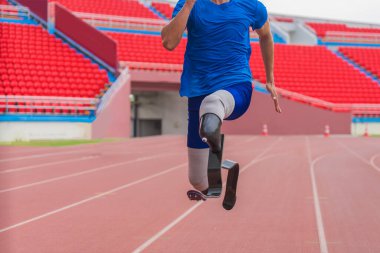Protezleri olan Asyalı erkek sporcu son sürat koşuyor. Stadyum pistinde güçlü bir uygulama sergiliyor.