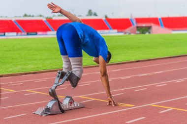 Seçici olarak protezlere odaklanan Asyalı erkek sporcu, stadyumda hızlı koşuya hazırlanıyor.