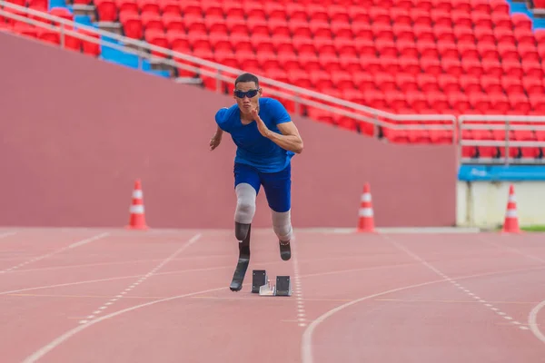 Asian male athlete, prosthetics user, sprints off from block start, powering his practice run on stadium track
