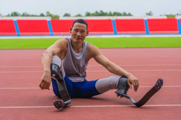 Elated Asian speed runner, donned in two prosthetic running blades, sits on the stadium track, taking a breather after a fulfilling speed running practice session