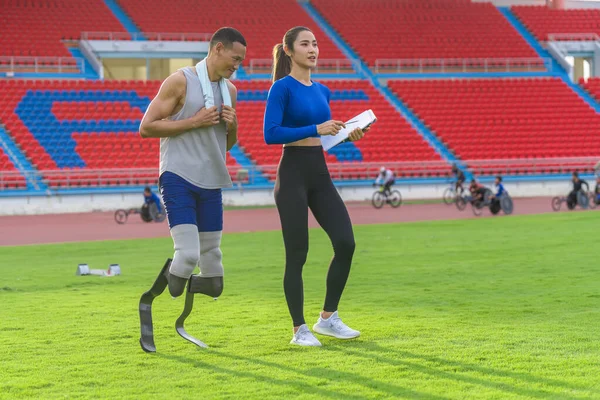 stock image Male athlete with prosthetic blades, alongside female trainer, outlining the day's speed running training at the sports stadium