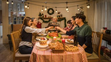 Mutlu Asyalı bir aile, çok nesildir Noel ve Şükran Günü kutlamalarında yemek odasında kadeh kaldırıyor.