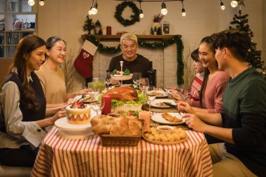 Şükran Günü ve Noel kutlamalarında Asyalı mutlu bir aile. Geleneksel ev yemeği.