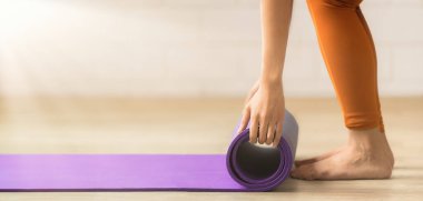 Eller dikkatle mavi yoga minderini sarıp yenilenme seansının bittiğinin sinyalini veriyor.
