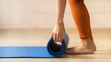 Eller dikkatle mavi yoga minderini sarıp yenilenme seansının bittiğinin sinyalini veriyor.