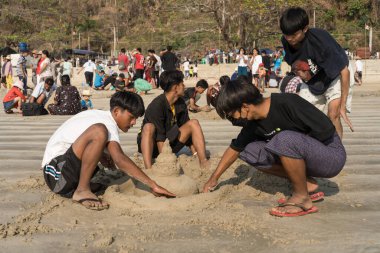 Ngapali plajı, Rakhine, Myanmar, Mart 2023: Ngapali Sonbahar Festivali 'ne katılanlar sahildeki geleneksel kum heykeli sanatıyla ilgileniyorlar
