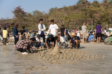 Ngapali plajı, Rakhine, Myanmar, Mart 2023: Ngapali Plaj Festivali 'nde yerel Myanmar halkı, sahildeki geleneksel kum heykeli sanatıyla ilgilenir.