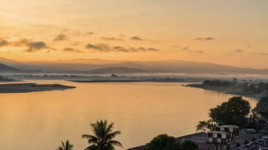 Irrawaddy Nehri 'nin üzerinde nefes kesen altın gündoğumu. Myitkyina, Myanmar' dan görüldüğü gibi. Uzak dağların siluetleri ve sakin nehirler sabah erken ışıklarını yansıtıyor.