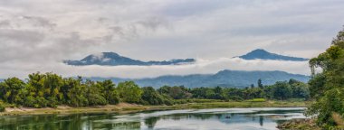 Kaungmulone Köprüsü 'nden gelen sakin Mali Kha Nehri' nin panoramik manzarası, Putao, Kachin Eyaleti, Myanmar 'daki sisli dağlar ve yemyeşil alanla çevrili.