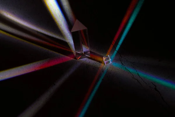 ガラスの立方体と三角形のプリズムは 暗闇の中の色を反映する — ストック写真