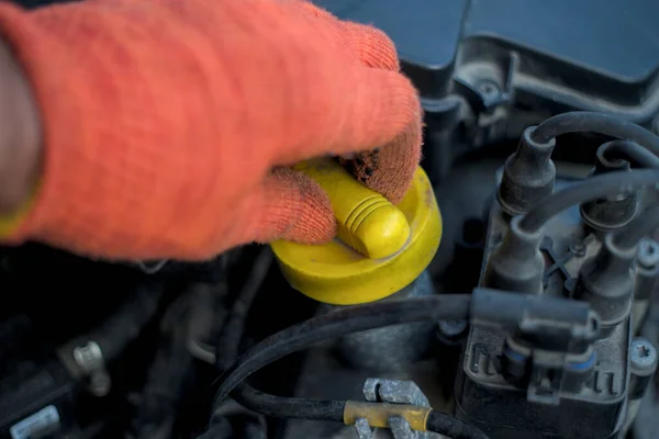 Auto mechanic is opening the oil cap to fill the motor oil to engine , auto maintenance service concept