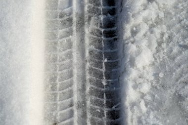 Kar yüzeyinde tekerlek izleri. Eriyen kar. Güneşli kış günü.