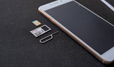 Teplyk, Ukrayna, Haziran 06, 2024: cep telefonu ve nano SIM kartlar, mikro SD sürücü ve koyu arkaplanda metal anahtar