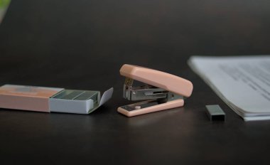 Masanın üzerinde zımba ve kağıt olan pembe zımba.