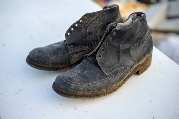 stock image Pair of old black worn shoes on white surface