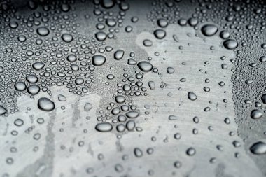 Gümüş metal yüzeyine su damlaları düşüyor. Yaklaş.