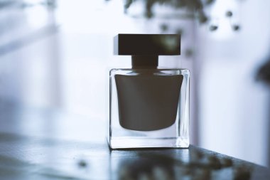 Beyaz arka planda, güneş ışığı ve yaprakların gölgesi olan bir parfüm şişesi.