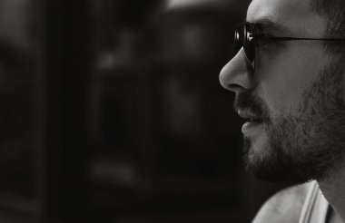 Güneş gözlüklü bir adamın siyah beyaz portresi.