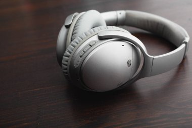 Ahşap bir masada gümüş kulaklıklar.