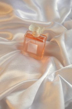 Beyaz ipekli kumaş kaplamalı parfüm şişesi. Koku kozmetik.