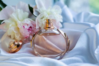 Hafif arka planda parfüm şişesi ve çiçekler.