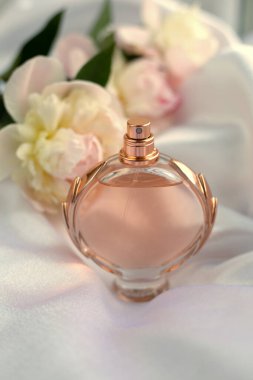 Hafif arka planda parfüm şişesi ve çiçekler.