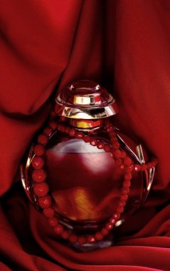 Bir şişe kırmızı parfüm ve kırmızı boncuk.