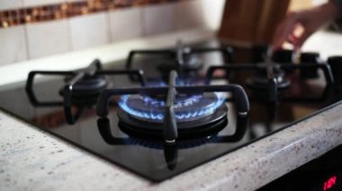 Bir kadın gaz ocağını yakıyor.