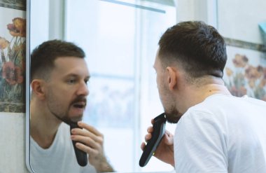 Adam aynanın önünde tıraş oluyor.