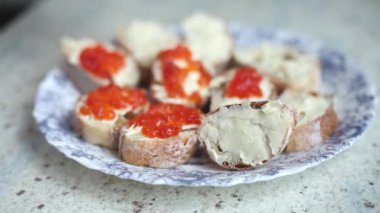 Bir adam somon havyarlı sandviç yapıyor.