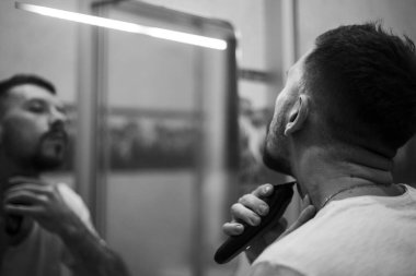 Tıraş olan bir adamın siyah beyaz fotoğrafı.