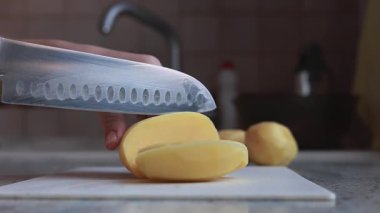 Bir kadın yemek pişirmek için patates keser.