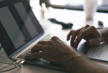 Masada yeni bir iş projesi üzerinde çalışırken dizüstü bilgisayar başında genç ofis yöneticisinin elleri