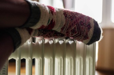 Isıtıcının yanında çoraplı kadın bacakları.