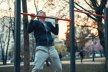 Sağlığını korumak için spor alanında barfiks çeken bir adam.