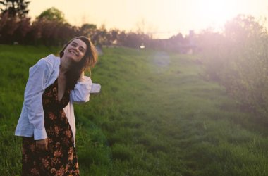 Güzel bir kadın doğada gün batımının tadını çıkarıyor.