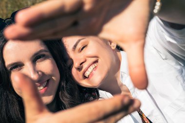 Kameraya gülümseyen çekici kız kardeşlerin açık hava portresi. Kafkasyalı mutlu kızlar arkadaşlığın tadını çıkarıyor..