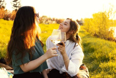 Güzel kızlar gün batımında şarap içiyor.