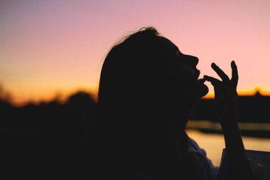 Güzel kadın gün batımında doğanın tadını çıkarıyor.