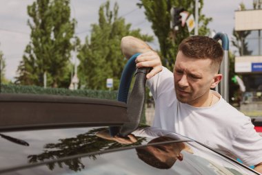 Bir adam araba süpürür.